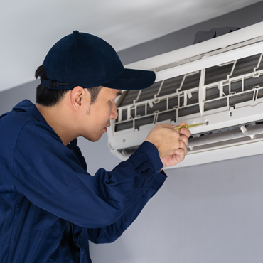 Technician performing maintenance on a residential air conditioning unit, ensuring optimal performance and efficiency for Hidalgo County homeowners.