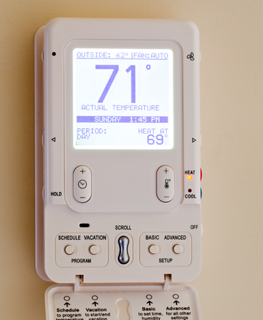 Thermostat displaying current temperature settings, including outside temperature and time, illustrating modern HVAC control for energy efficiency and comfort.