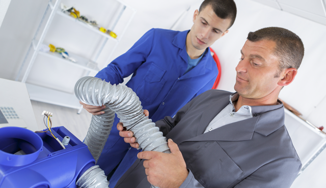 Technicians inspecting and handling flexible ductwork during HVAC repair, emphasizing expertise in duct and vent services at L&S Air LLC.