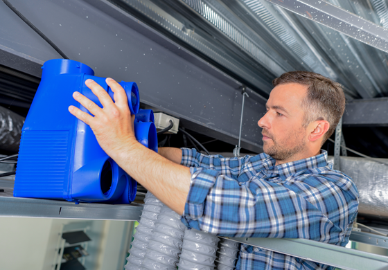 Man adjusting blue ductwork component in HVAC system, emphasizing professional duct and vent repair services by L&S Air LLC.