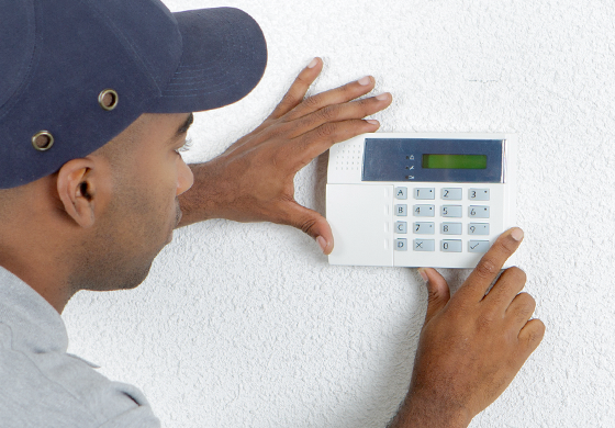 Technician adjusting a digital thermostat on a wall, showcasing HVAC repair expertise for smart home systems.