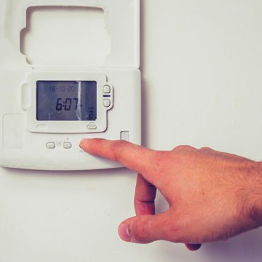 Hand adjusting a digital thermostat displaying the time, illustrating HVAC troubleshooting and repair services offered by L&S Air LLC in the Rio Grande Valley.